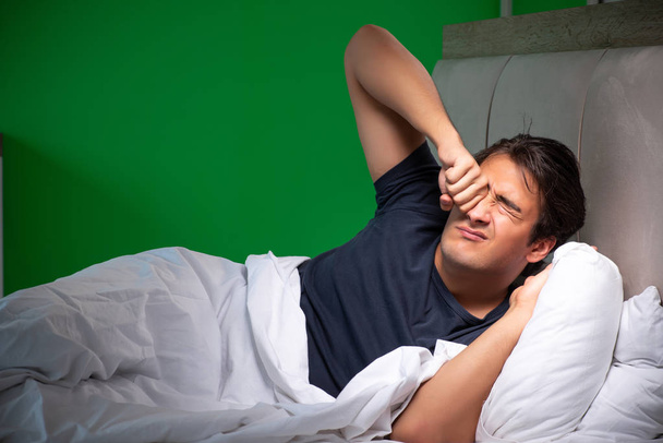 Jonge knappe man lijdt aan slapeloosheid thuis - Foto, afbeelding