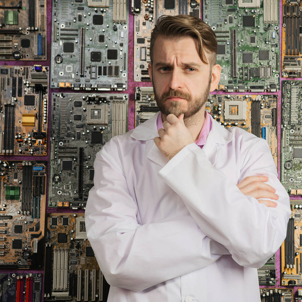 contemplative electronics engineer stands near the wall of motherboards. - Photo, Image