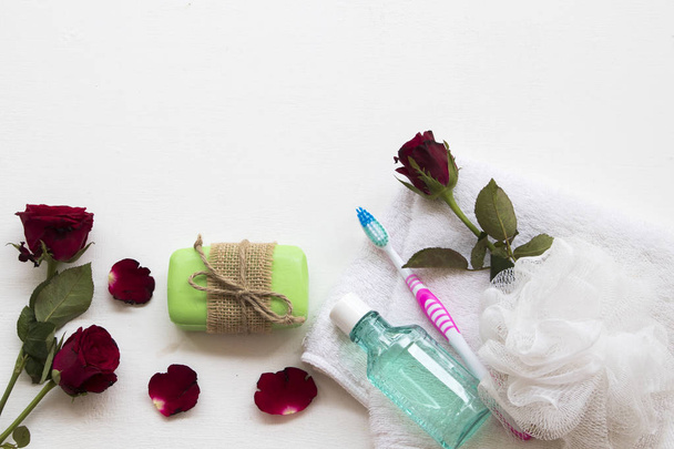 Kräuterseife, Frottee Gesundheitsvorsorge für die Körperhaut mit Mundwasser, Zahnbürste für die Mundhöhle bereiten ein Bad und Blume Rose auf Hintergrund weißen Holz - Foto, Bild