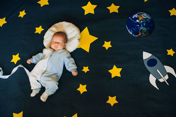 baby boy sleeps on the background of the starry sky with a rocket and planet - Zdjęcie, obraz