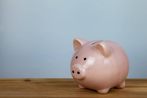 Pink pig money box on a wooden background close up. - Zdjęcie, obraz