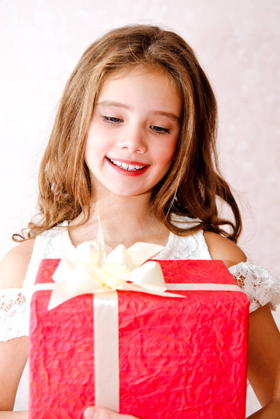 Happy little girl holding red gift box in christmas time closeup - Foto, Imagem