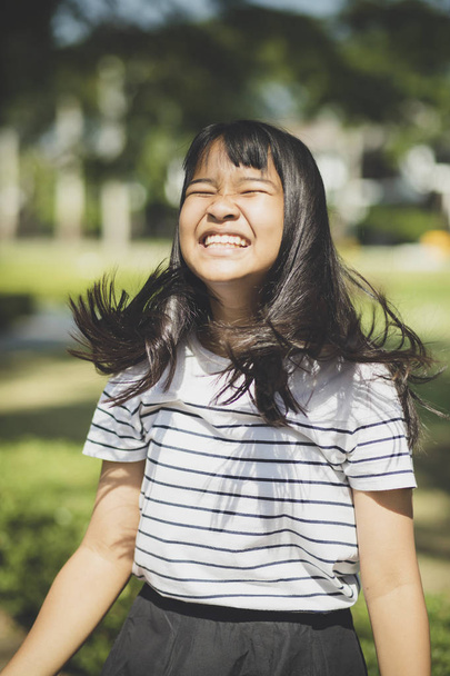 Witzgesicht eines asiatischen Teenagers zeigt vom Wind fließendes Vorderlockenhaar - Foto, Bild