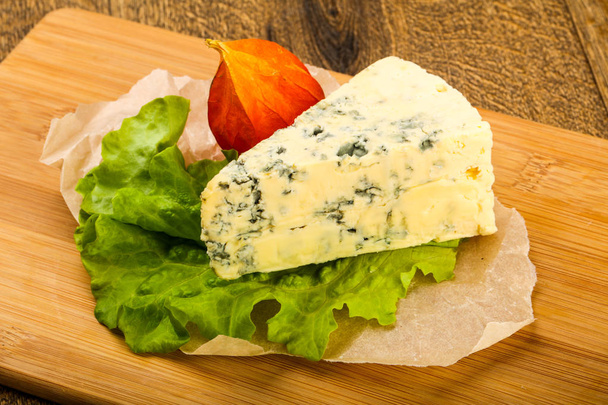 Blue cheese with salad leaves over the wooden background - Photo, Image