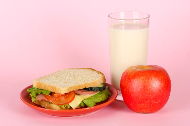 broodje op plaat met apple en melk op roze achtergrond - Foto, afbeelding