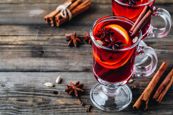 Glühwein mit Gewürzen und Orange im Glas auf rustikalem Holzgrund. hausgemachtes Weihnachtsgetränk. - Foto, Bild