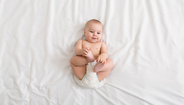 Cute baby lying on bed at home, top view - Photo, image