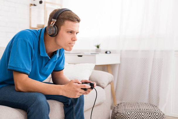 Концентрований хлопець грає у відеогру з джойстиком
 - Фото, зображення