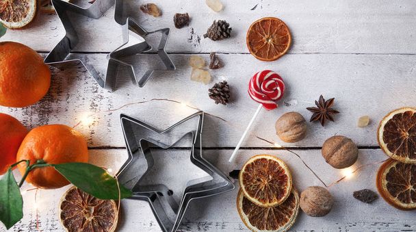 Christmas or New Year decoration, fir tree, tangerine, candy cane, dry oranges, sugar, walnuts and cookie cutters  - Photo, image