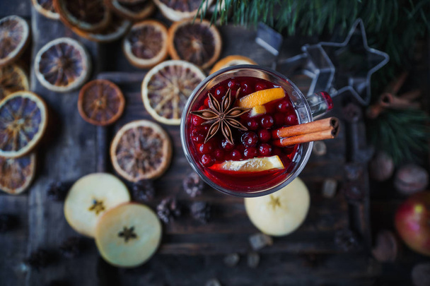 Homemade mulled wine with oranges, apples, cinnamon, cranberries and fir tree on rustic wooden background - Фото, зображення
