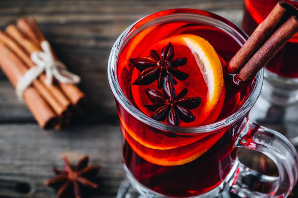 Vino rosso brulé con spezie e arancia in vetro su fondo rustico ligneo. Bevanda di Natale fatta in casa
. - Foto, immagini