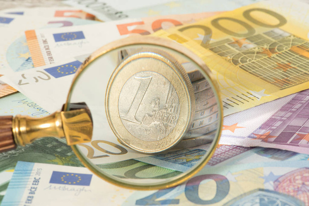 A magnifying glass, euro bills and euro coins - Photo, Image