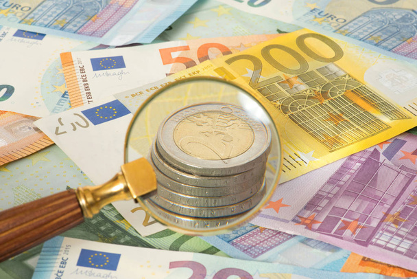 A magnifying glass, euro bills and euro coins - Photo, Image