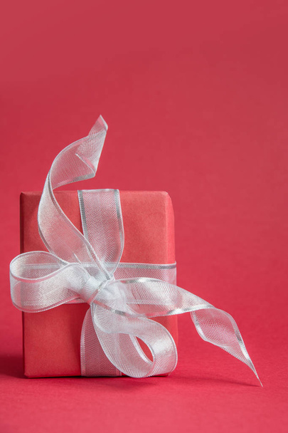 Red christmas giftbox with silver ribbon on red. Space for wishes. - Φωτογραφία, εικόνα