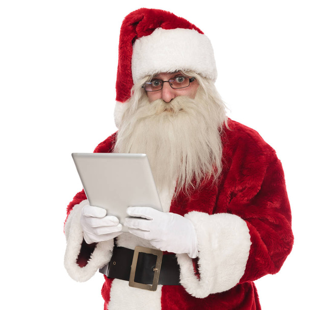 portrait of saint nick holding a grey tablet while standing on white background - 写真・画像