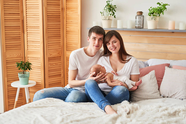 young parents with a newborn baby at home on the bed - Photo, Image