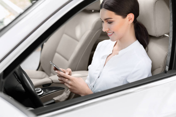 Business woman sitting in car, using mobile phone - Фото, изображение