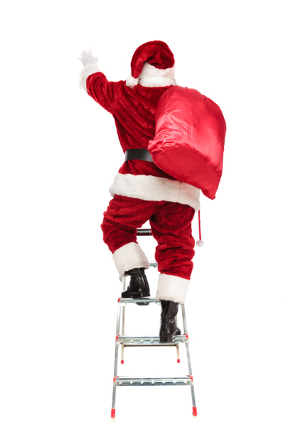 vue arrière du Père Noël étirant la main tout en montant l'échelle et debout sur fond blanc, image pleine longueur
 - Photo, image