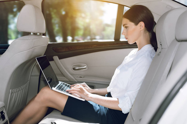 Mujer de negocios trabajando en el ordenador portátil en el asiento trasero en el coche
 - Foto, Imagen