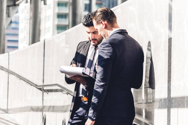 Imagen de dos socios de negocios en traje elegante negro hablando y trabajando juntos mientras se discute la nueva estrategia en la ciudad.Concepto de idea de negocio y startup
 - Foto, imagen
