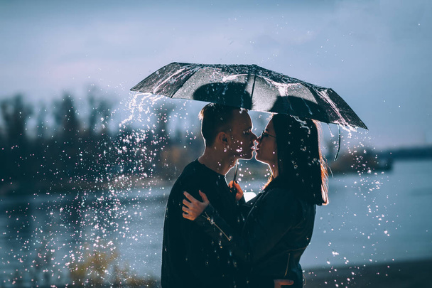 young couple standing under a dark umbrella. - Foto, Imagem