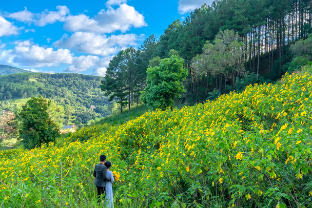 丘の中腹に一緒にカップルが野生のヒマワリが咲くカラフルな美しい自然の景色、ダラット、ベトナムの自然の前に人間を幸福を覆われたダラット、ベトナム - 2018 年 10 月 27 日。 - 写真・画像