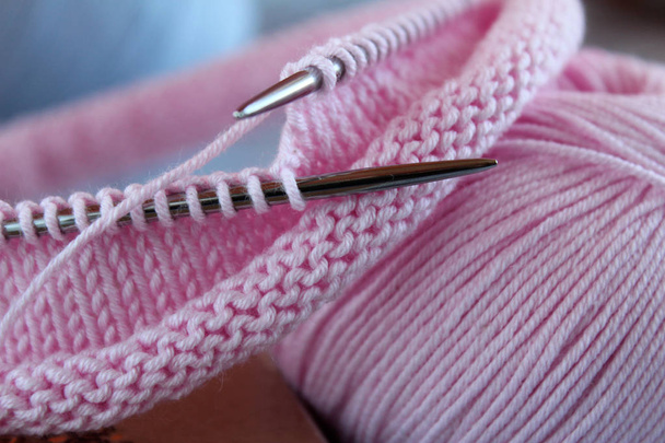 Des fils à tricoter roses, des aiguilles à tricoter et des boucles de tricot reposent sur la table. Texture de tricot
 - Photo, image