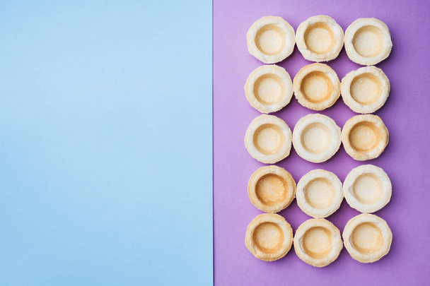 Empty shortbread tartlets laid out in a row. Abstraction concept in the color of the surface. Copy space - Φωτογραφία, εικόνα