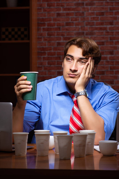 Empleado joven que bebe café trabajando en turno de noche
  - Foto, imagen