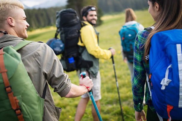 Hiking with friends is so fun. Group of young people with backpacks walking together and looking happy - Zdjęcie, obraz