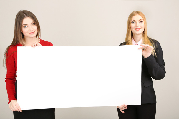 Two business women with blank form on grey background - Фото, изображение
