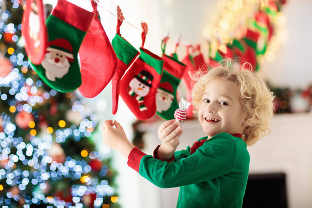 Діти відкривають різдвяні подарунки. Дитина шукає цукерки та подарунки в календарі пригод в зимовий ранок. Декорована ялинка для сім'ї з дітьми. Маленький хлопчик у піжамі Різдва
. - Фото, зображення
