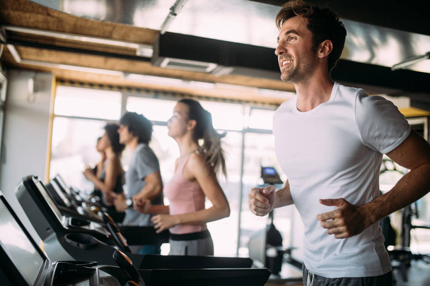 Young fit people running on a treadmill in health club. - Φωτογραφία, εικόνα