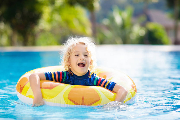スイミング プール、膨脹可能なおもちゃリング フロート付きの子。泳ぐし、トロピカル リゾートの屋外プールでダイビングを学ぶ少年。子供たちと一緒に泳ぐ。子供のための健康的なスポーツ活動。水の楽しみ. - 写真・画像
