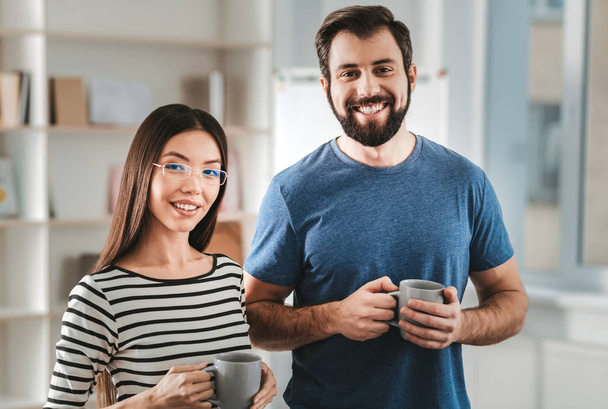 Beaming man with cup of tea in his hands standing near girlfriend - Foto, Imagem
