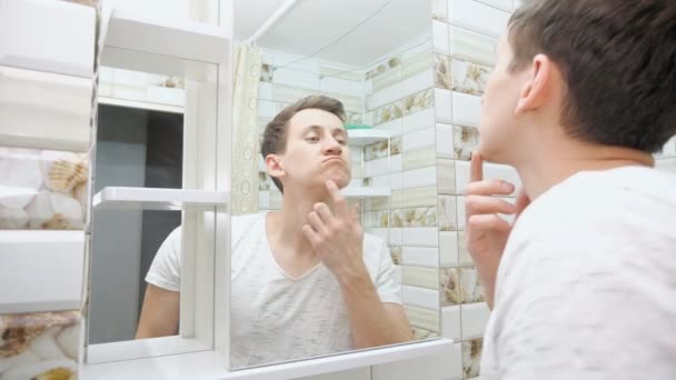 Junger Mann checkt seine Haut im Badezimmer - Filmmaterial, Video