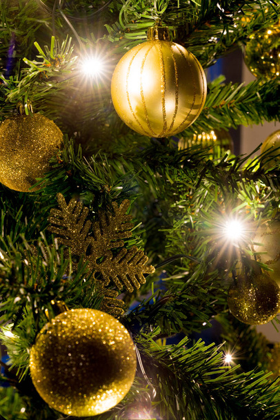 christmas tree with golden ornaments and bright shiny lights - Foto, afbeelding