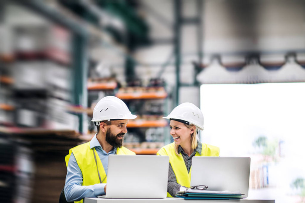 A portrait of an industrial man and woman engineer with laptop in a factory, working. - Foto, Bild