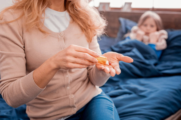Blonde woman preparing pills for a daughter - Photo, Image