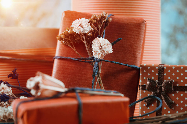 Composition horizontale avec des boîtes-cadeaux enveloppées dans du papier de couleur terre cuite naturelle, attachées avec de la ficelle, décorées de fleurs séchées
. - Photo, image