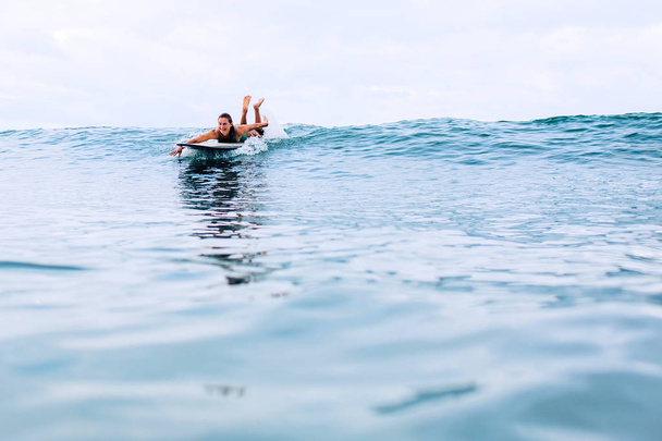 beautiful girl surfer swims on a board in the indian ocean on bali island - Fotó, kép