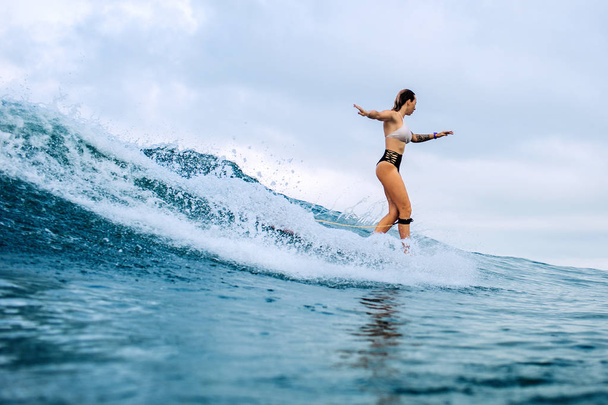 beautiful surfer girl riding on a board in the ocean on bali island - Photo, image