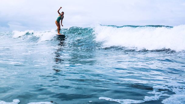 beautiful surfer girl riding on a board in the ocean on bali island - Zdjęcie, obraz