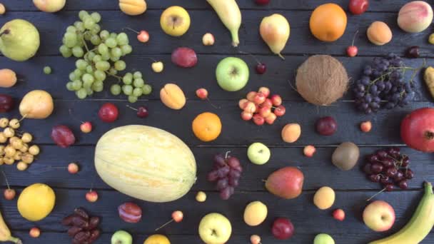 Meyve siyah ekolojik zemin üzerine. Üstten görünüm. Çeşitli meyveler siyah ahşap Eko arka plan üzerinde yer alır. Eko masanın üstünde: coconat, üzüm, portakal, muz, kiraz, limon, mandalina, şeftali, armut. - Video, Çekim
