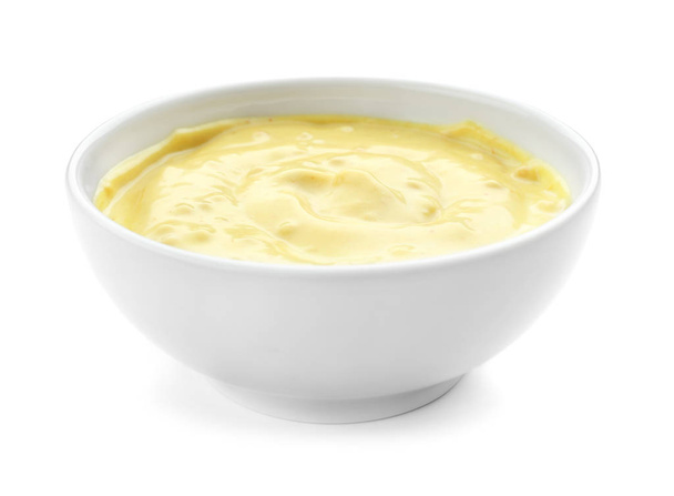 Smakelijke gele saus in kom op witte achtergrond - Foto, afbeelding