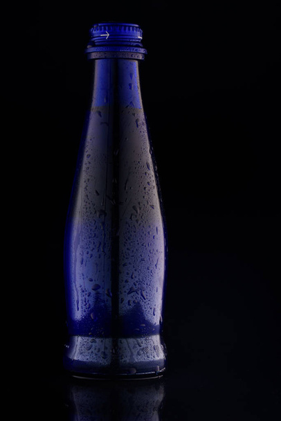 Blue beautiful bottle on a black background - 写真・画像