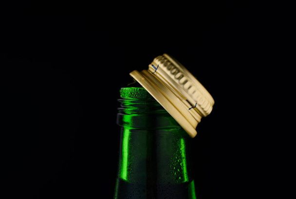 grüne Glasflasche auf schwarzem Hintergrund ins Licht geschossen - Foto, Bild