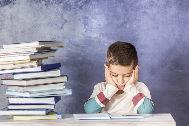 Little kid stressed doing homework with a stack of books - Фото, изображение