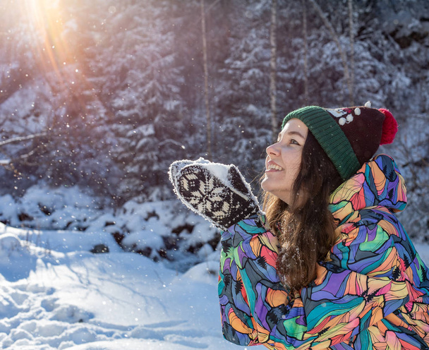 Різдвяний портрет дівчини на відкритому повітрі. Зимова жінка дме сніг у парку
 - Фото, зображення