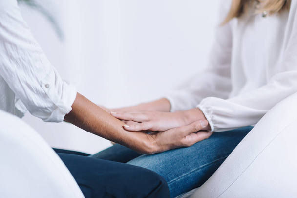 Female Theta healing therapist performing alternative therapy treatment with young woman patient. Therapist holding hands and transfer energy. Wearing white clothes. - Fotoğraf, Görsel